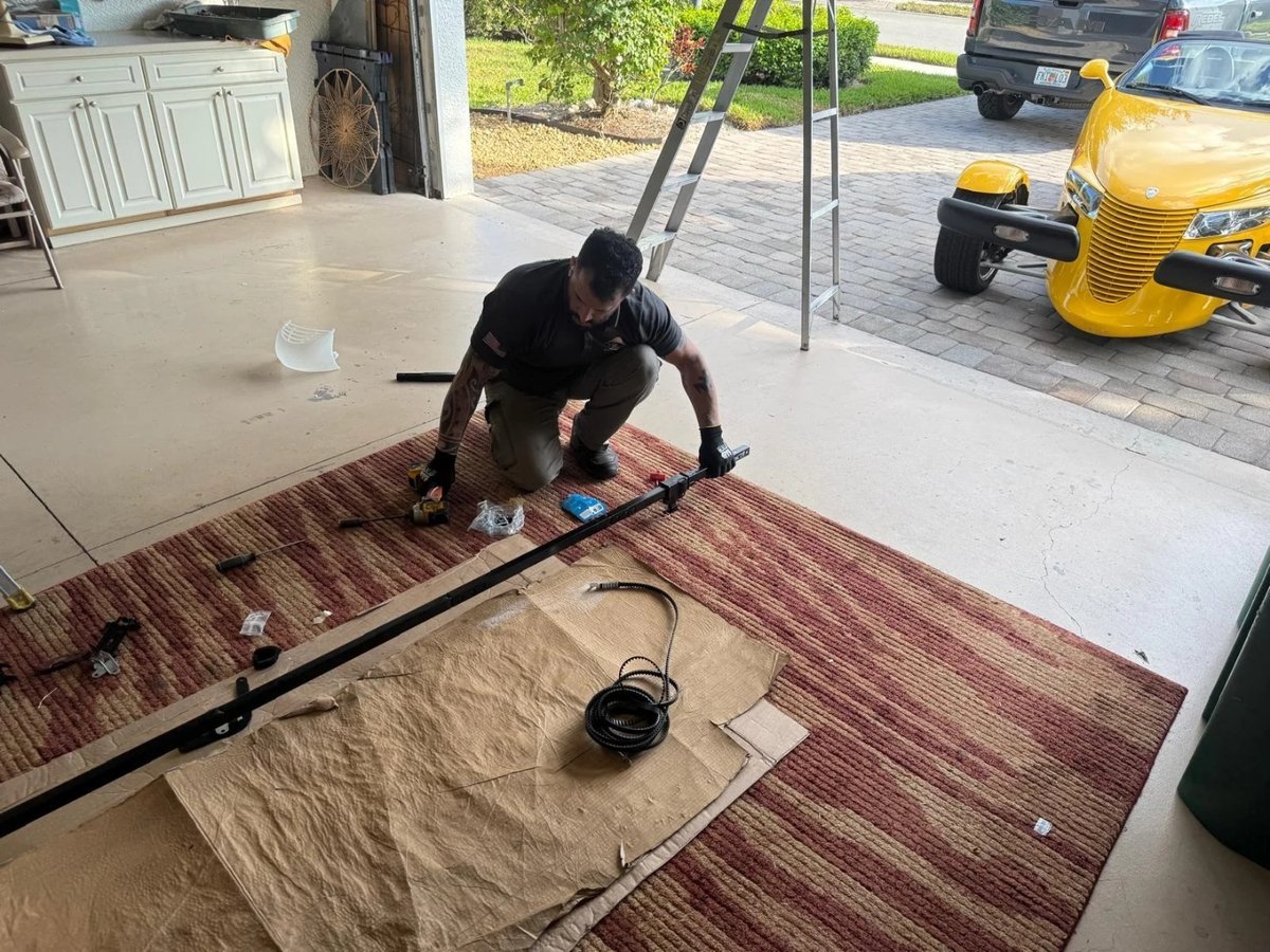 A person working beside a long opener rail on a garage floor